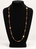 Brown bronze and gold beaded statement necklace on black jewelry display