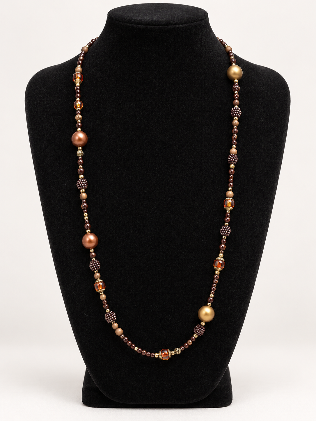 Brown bronze and gold beaded statement necklace on black jewelry display