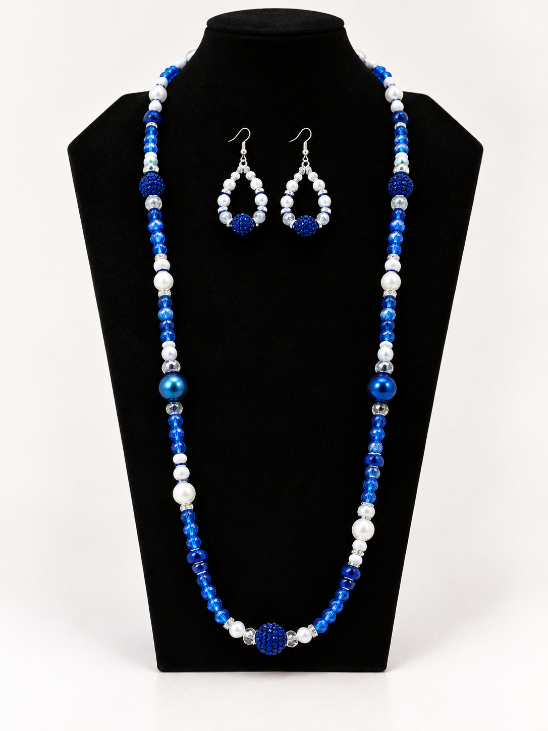 Royal blue and white beaded necklace with matching earrings on black jewelry display