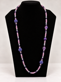 Pink and purple crystal beaded statement necklace on black jewelry display