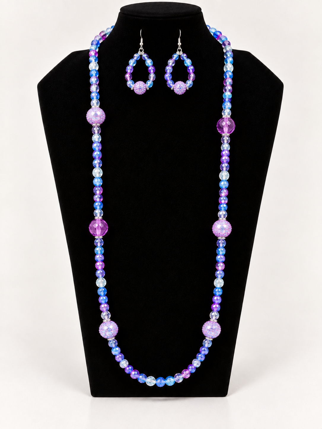 Purple and blue iridescent beaded necklace with matching earrings on black jewelry display