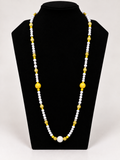 White and yellow beaded statement necklace on black jewelry display