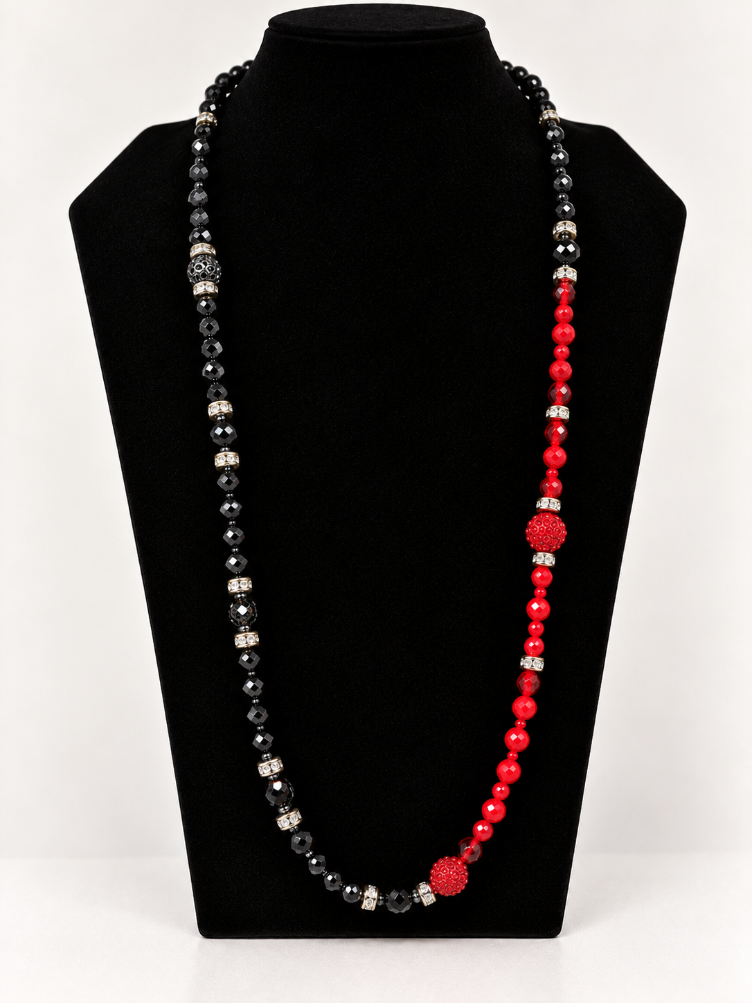 Black and red asymmetrical beaded statement necklace on black jewelry display