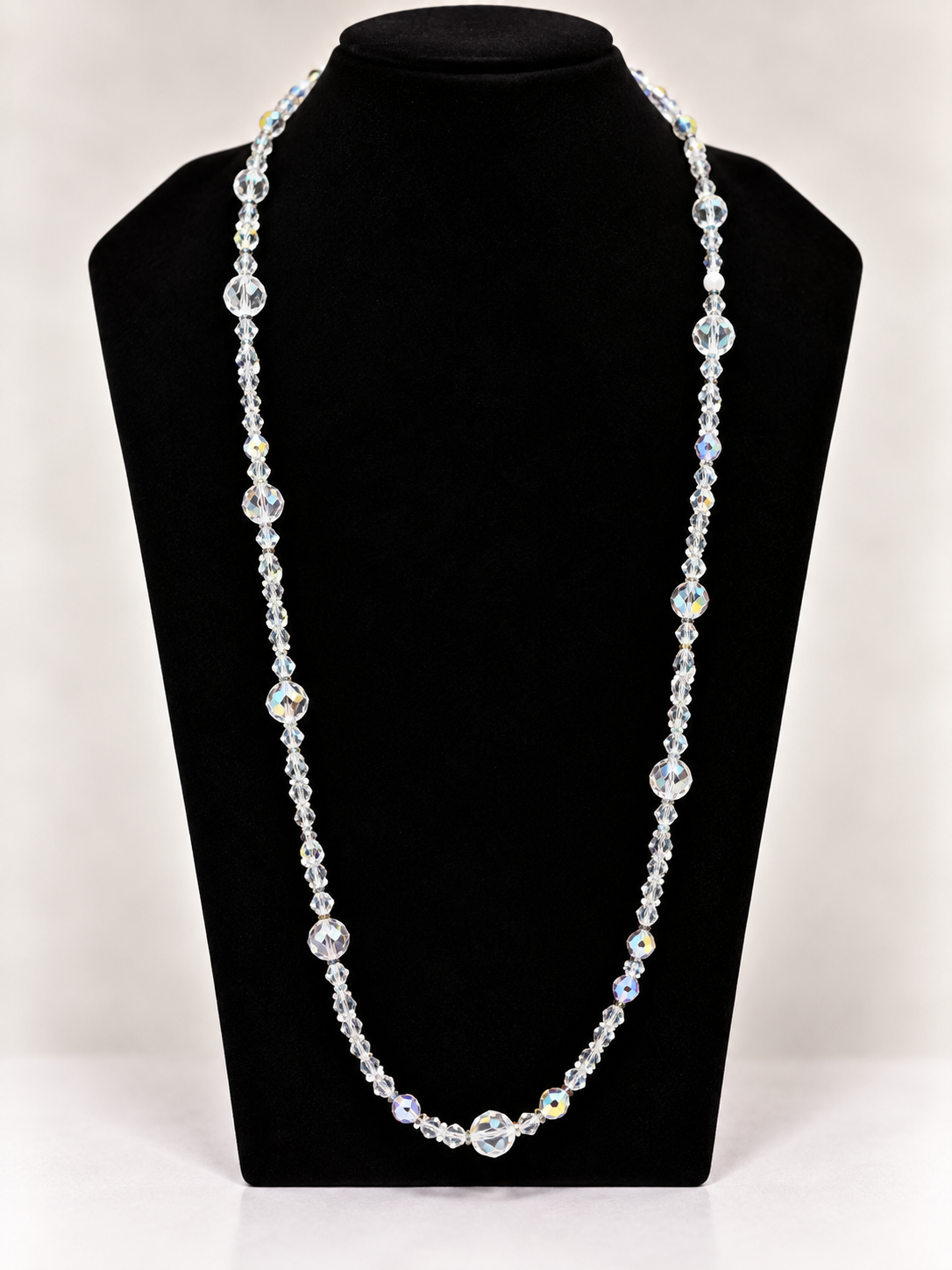 Clear iridescent crystal beaded necklace on black jewelry display