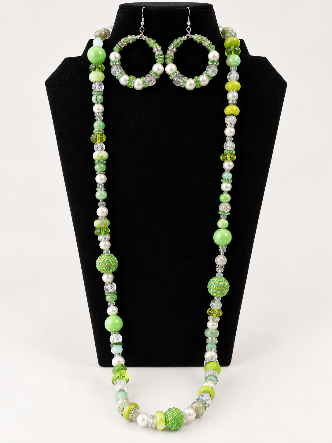 Green pearl and crystal beaded necklace with matching earrings on black jewelry display