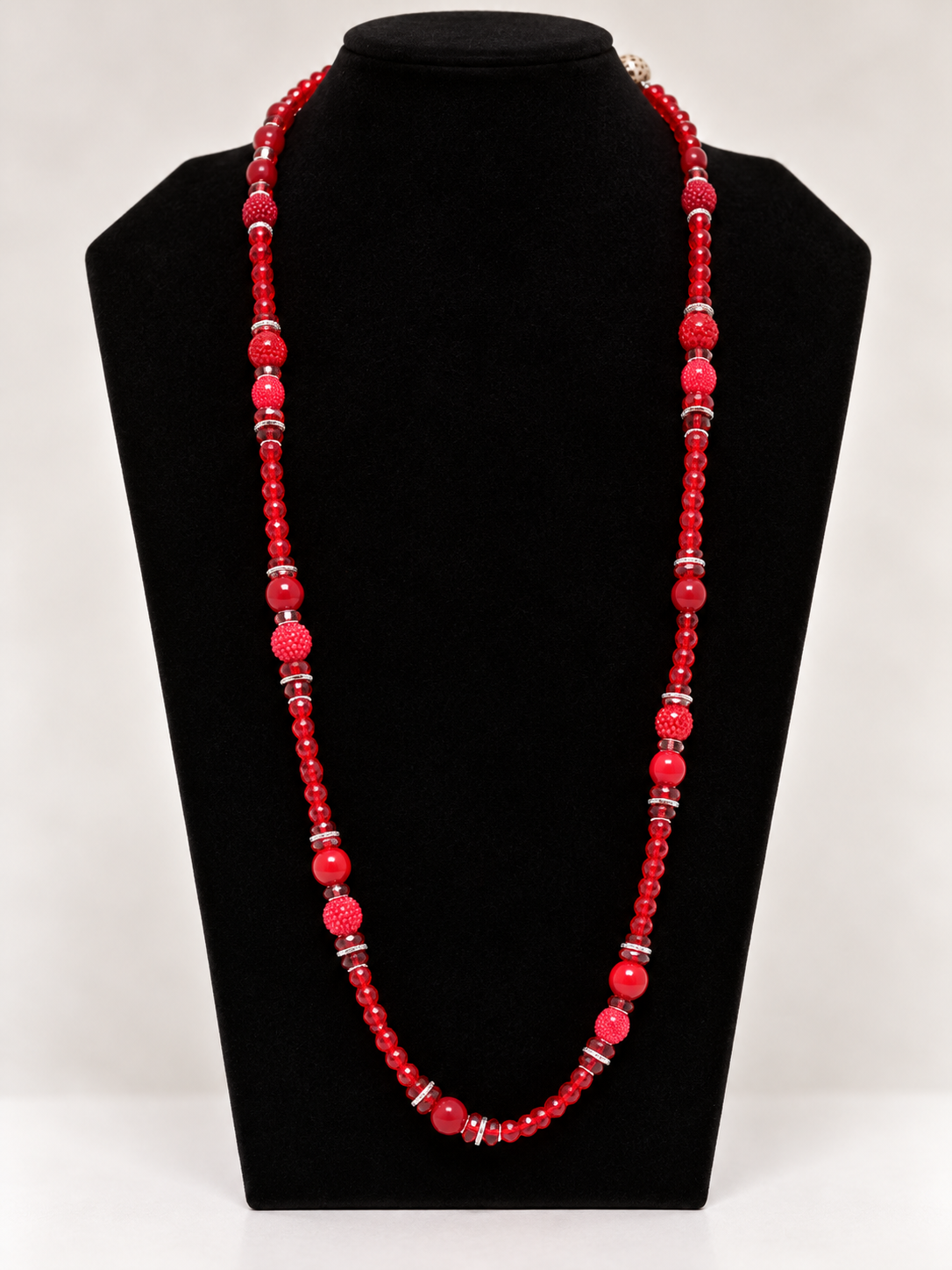 Red crystal and textured beaded statement necklace on black jewelry display